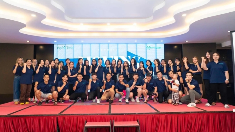Đội ngũ nhân sự TopOnSeek mặc đồng phục xanh navy chụp ảnh tập thể trên sân khấu tại sự kiện công ty SEO