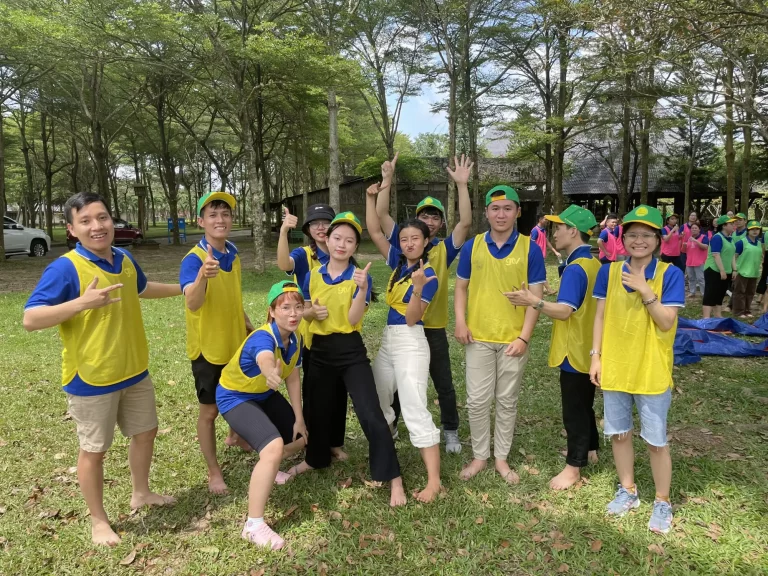 Thành viên GTV SEO mặc áo yếm vàng, đội mũ xanh tạo dáng giữa sân cỏ trong buổi team building